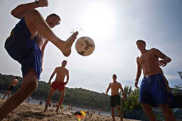 foto di due ragazzi che giocano a calcio in spiaggia