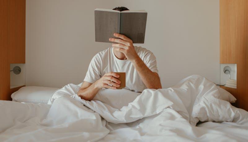 Uomo che legge un libro nel letto