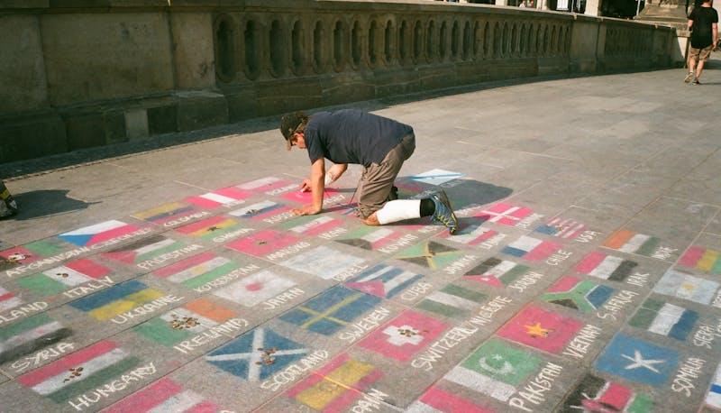 Uomo che disegna a terra delle bandiere