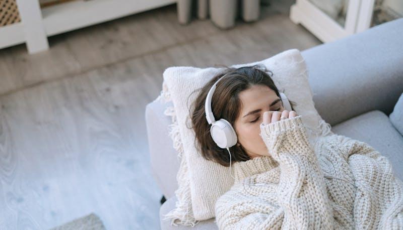 Studentessa ascolta musica sul divano con una mano sul viso