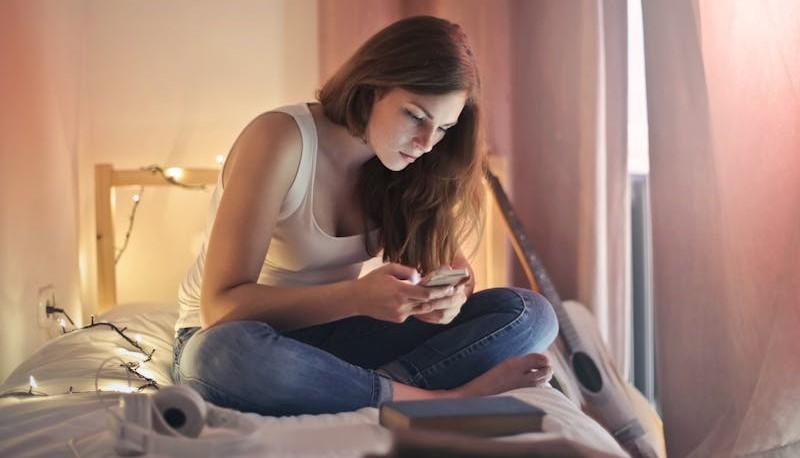 Ragazza che chatta sul letto durante il fenomeno del Benching
