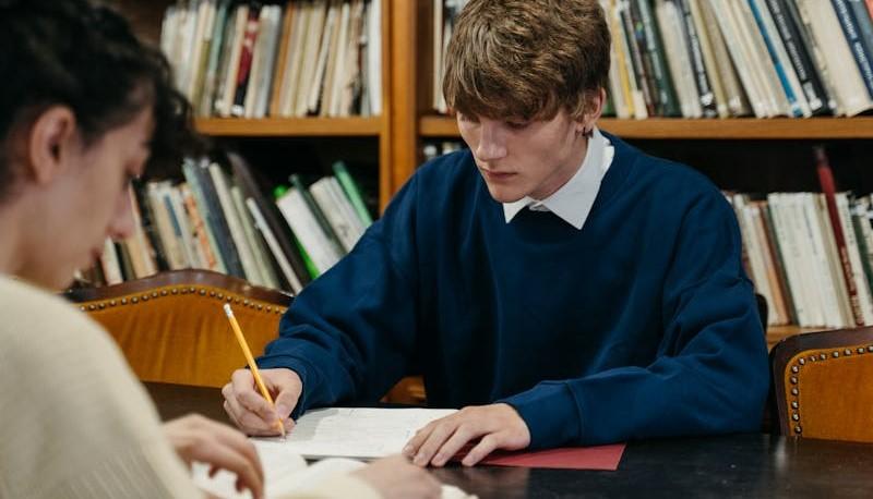 Due studenti innamorati che studiano in biblioteca