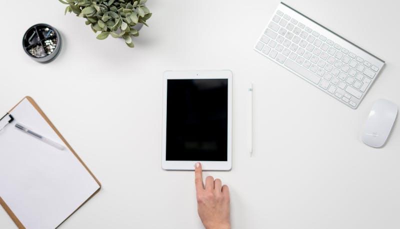 Scrivania con fogli, ipad e computer usati dallo studente per allenarsi alla seconda prova di Maturità per Grafica e Comunicazione