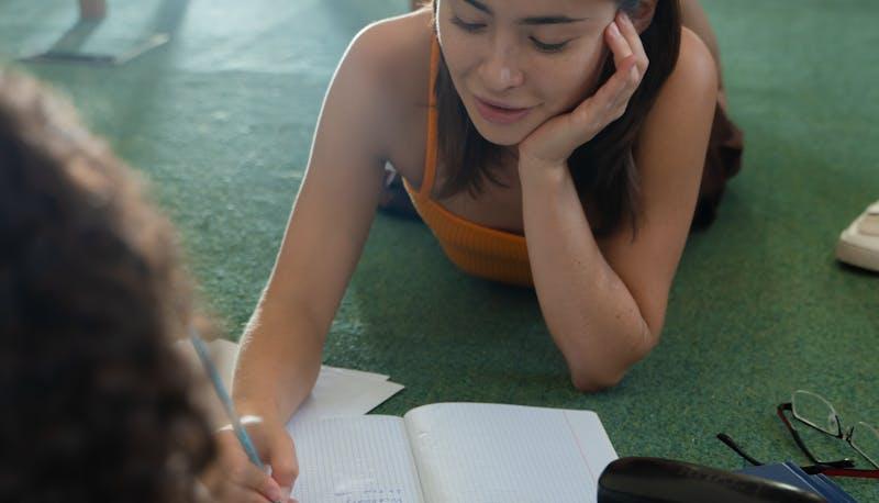 Studentessa di Scienze Umane che studia per la seconda prova distesa sul pavimento