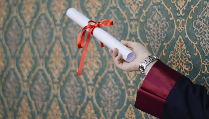 Neolaureato che stringe in mano la pergamena di laurea
