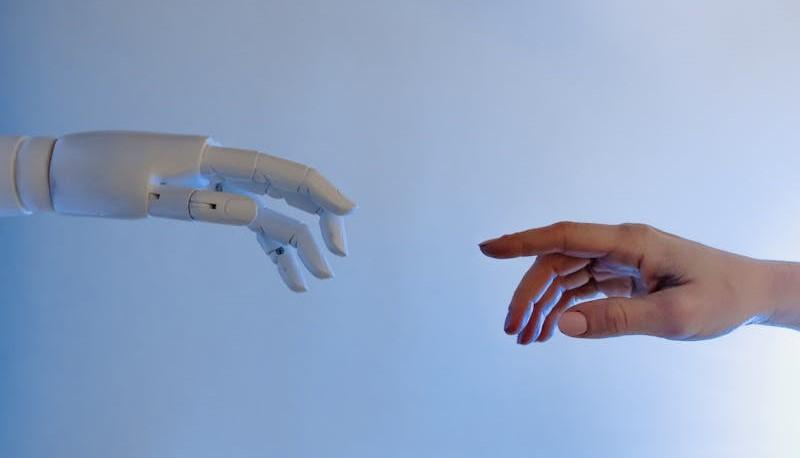 Mano di un'intelligenza artificiale che si sta per toccare con una mano umana
