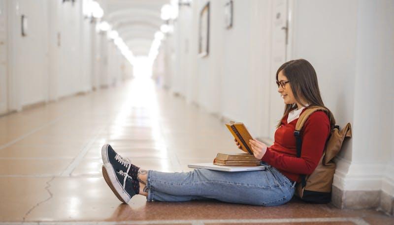 Studentessa fuori dall'aula che ripassa la materia di seconda prova