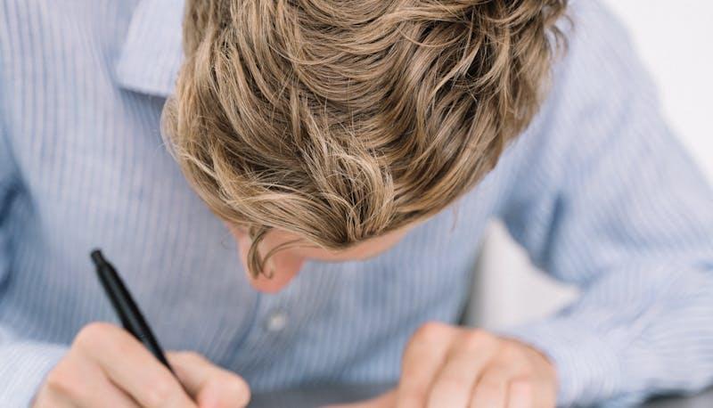 Studente all'esame di terza media mentre scrive il testo argomentativo