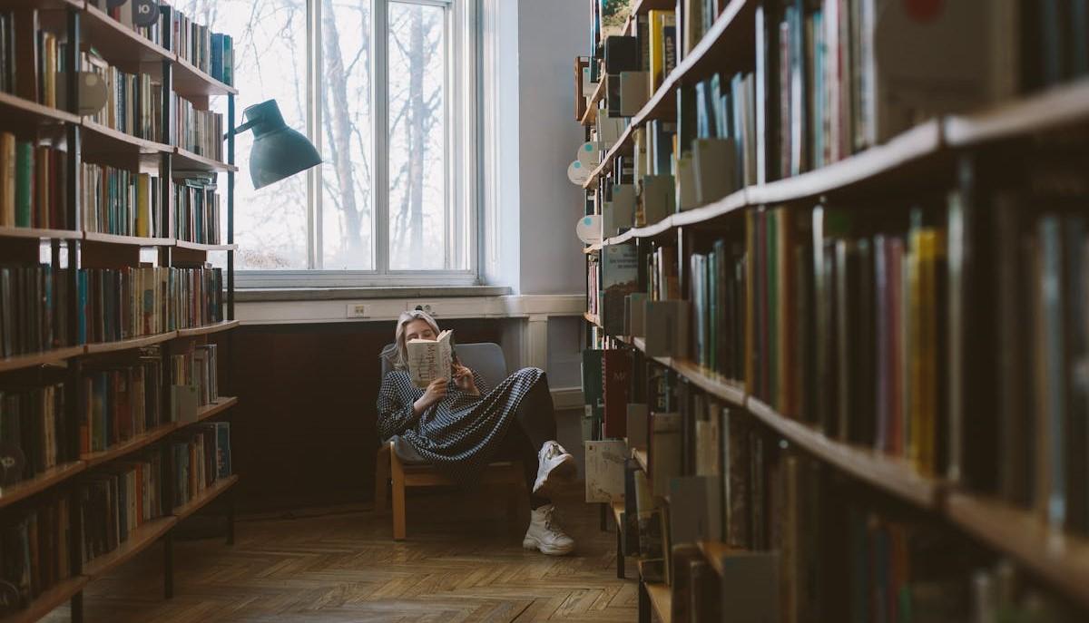 Studentessa di un corso umanistico che studia in biblioteca