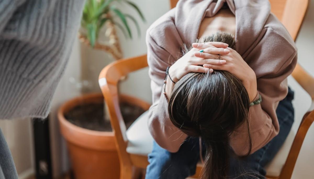 Studentessa disperata con la testa tra le mani perché rischia di perdere la borsa di studio per un esame annullato