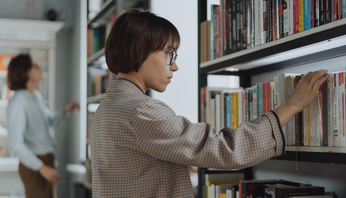 Studentessa cerca di capire in biblioteca come scegliere l'università che fa per lei