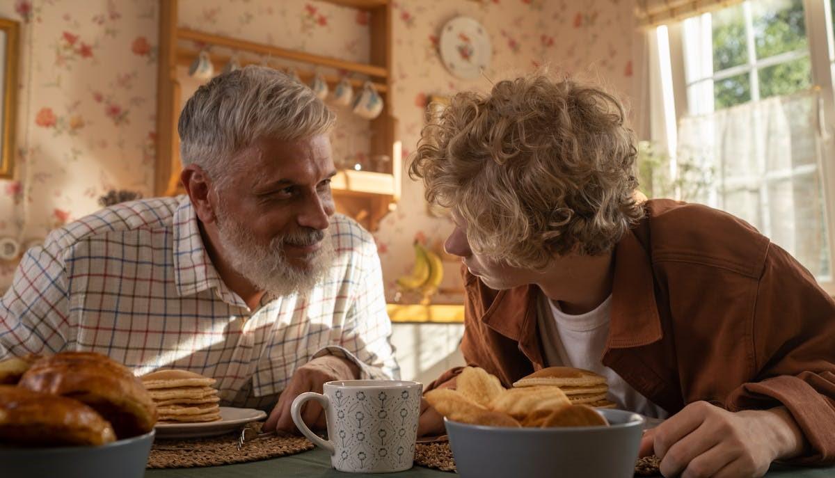 Nonno e nipote che si guardano mentre fanno colazione