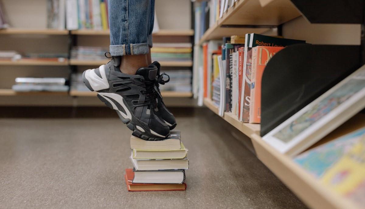 Matricola con i piedi sopra una pila di libri universitari
