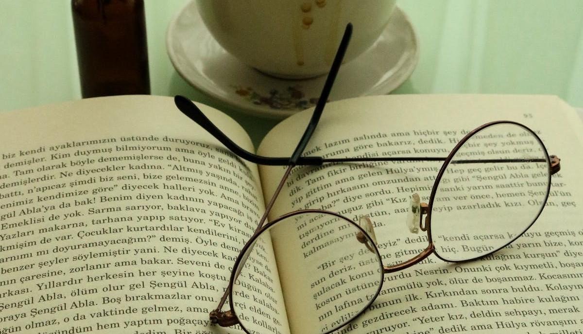 Libro aperto, occhiali da vista e tazza di caffè