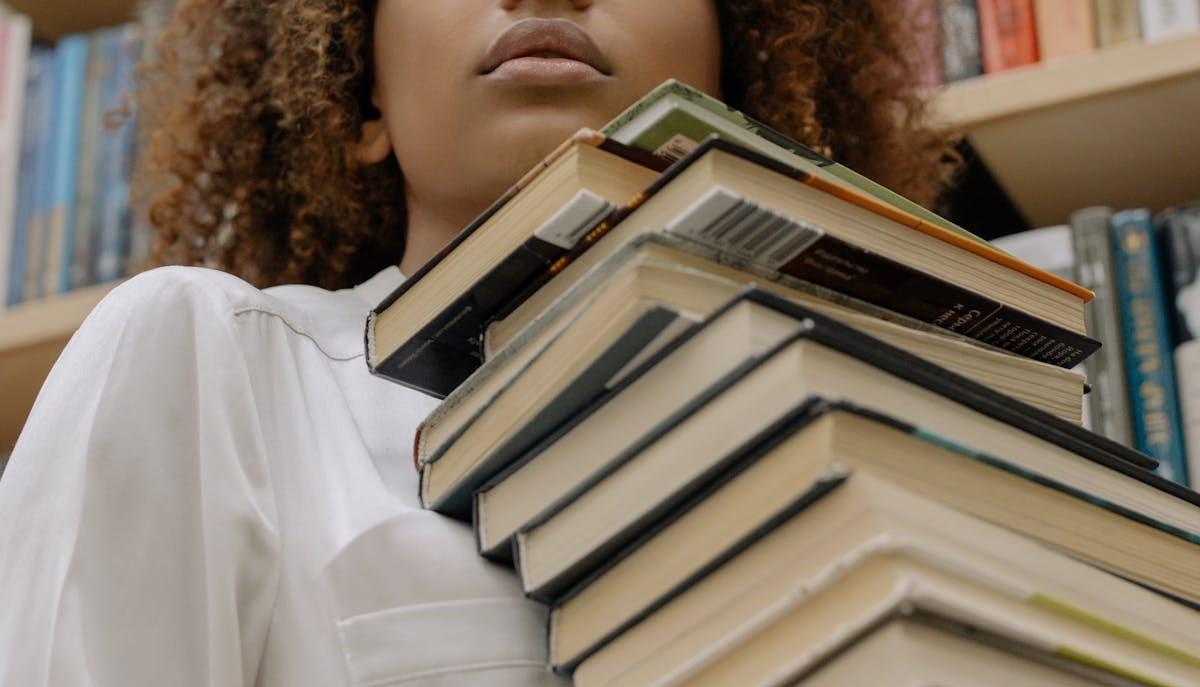 Studentessa con tanti libri per prepararsi alla seconda prova di Maturità