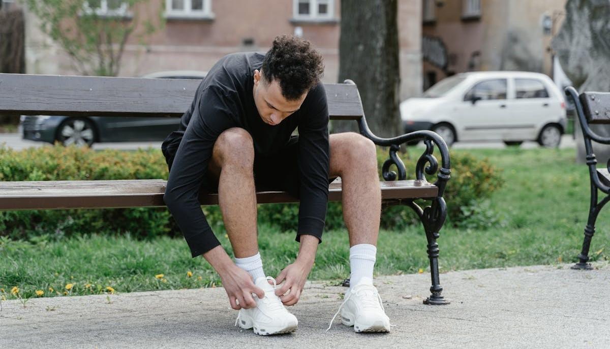 Ragazzo si allaccia una scarpa seduto su una panchina