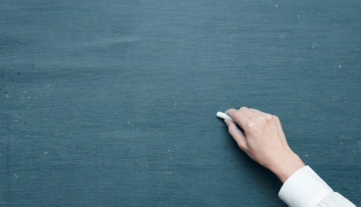 Professoressa di scuola superiore scrive con il gesso alla lavagna