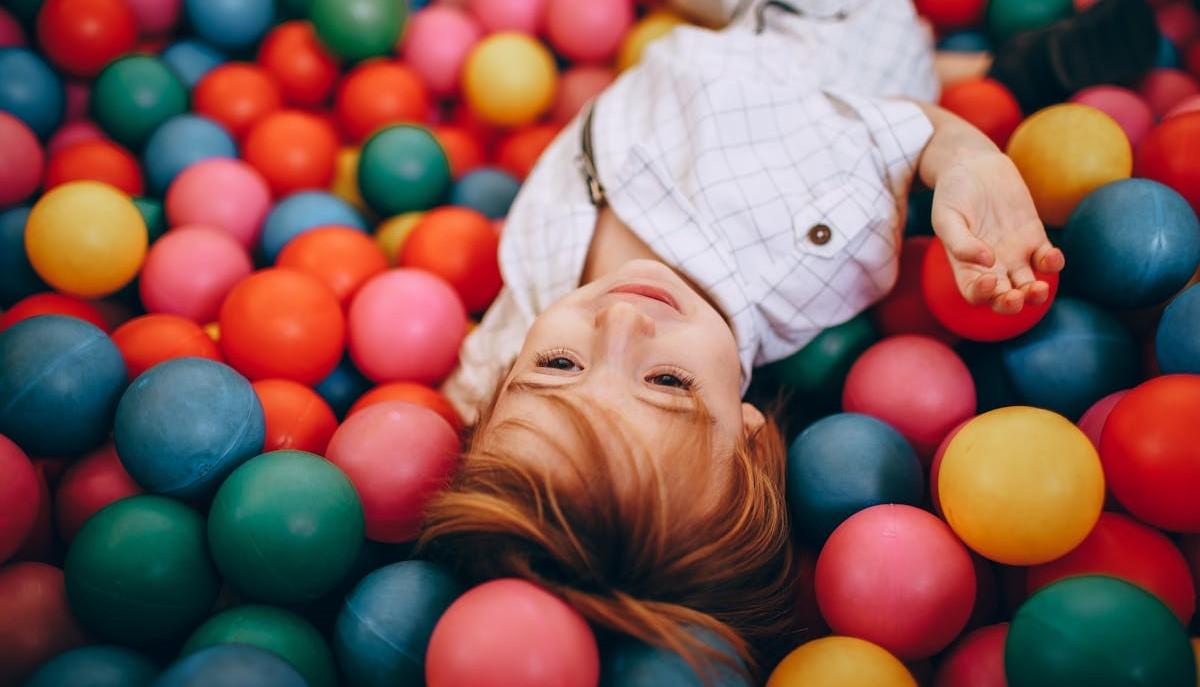 Bambino che gioca tra le palline colorate