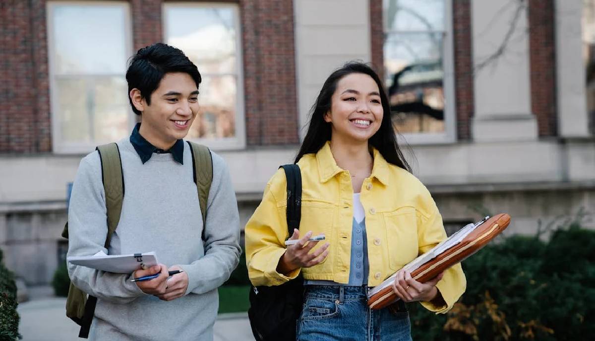 studentessa e studente camminano zaino in spalla