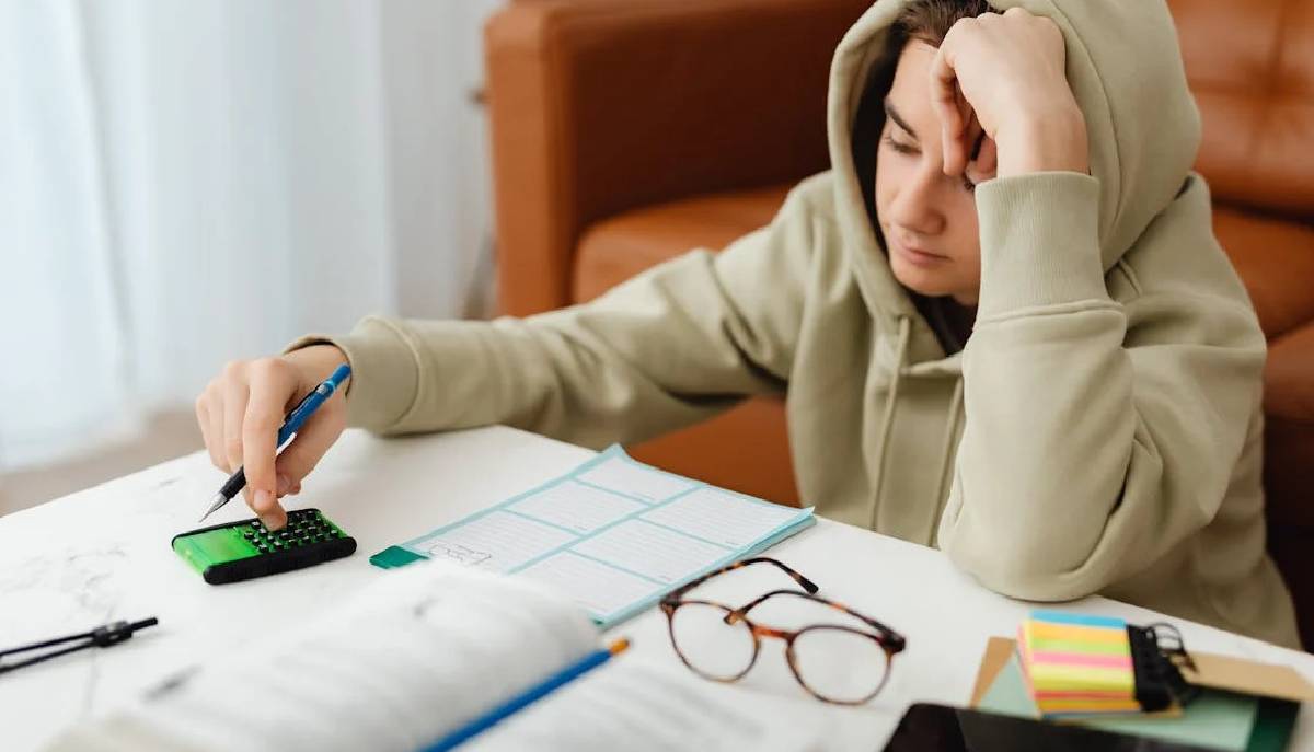 studente fa i compiti. Sulla scrivania ci sono fogli, quaderni, libri e una calcolatrice
