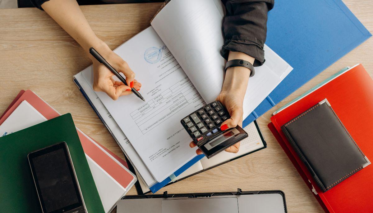 studentessa svolge esercizi con calcolatrice, sul banco ci sono libri e quaderni