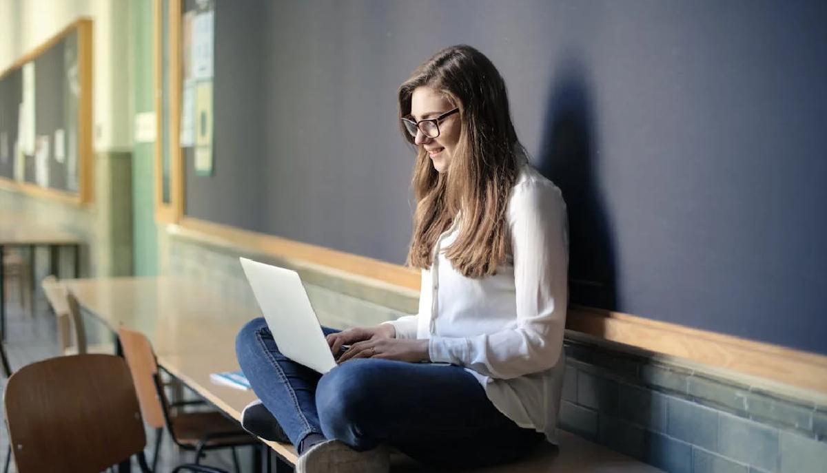 studentessa seduta su un banco scrive al pc