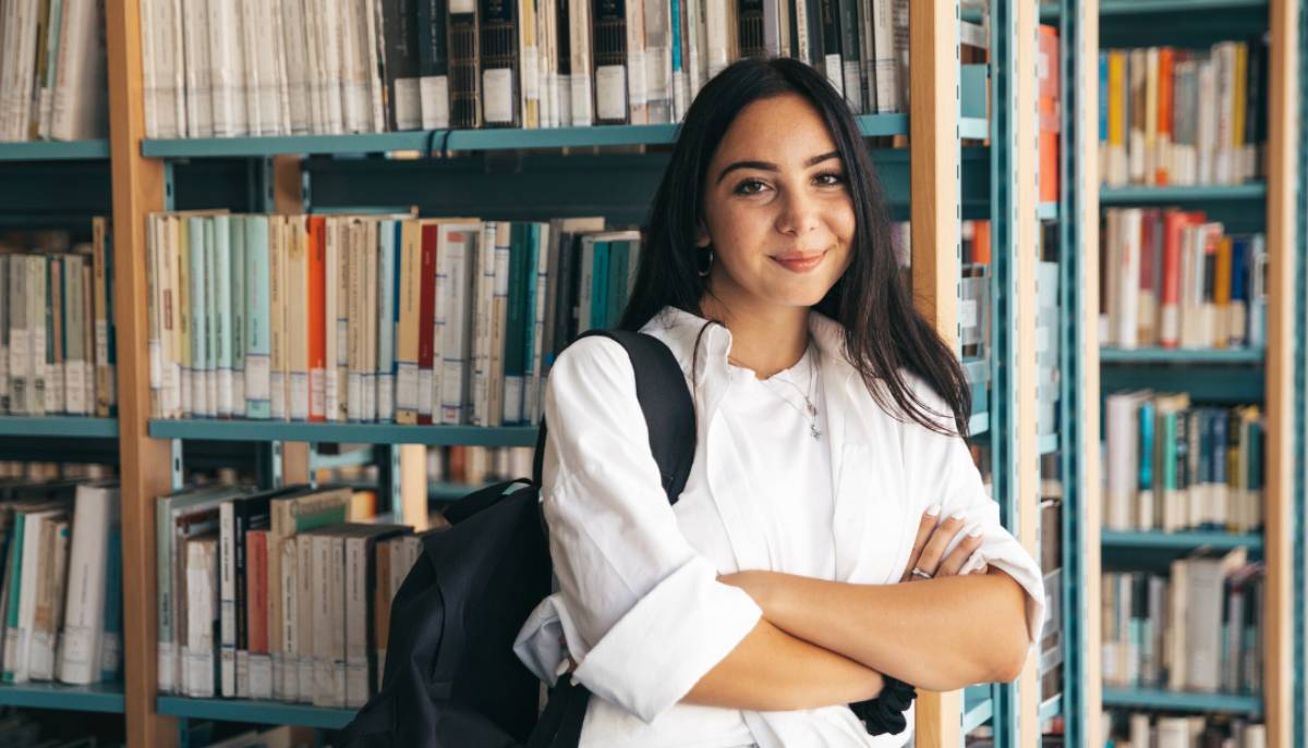 ragazza studentessa in biblioteca con braccia incrociate