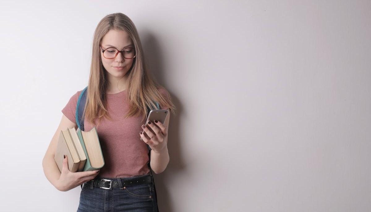Studentessa con smartphone e libri
