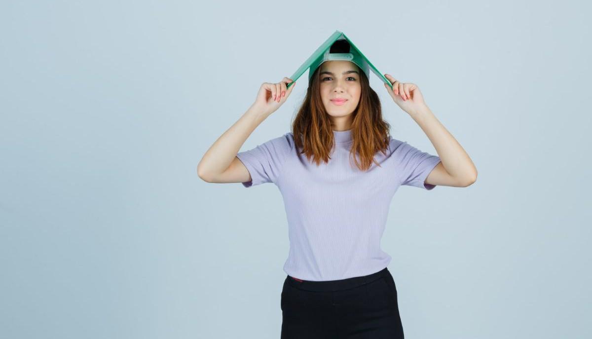 Studentessa con un quaderno in testa