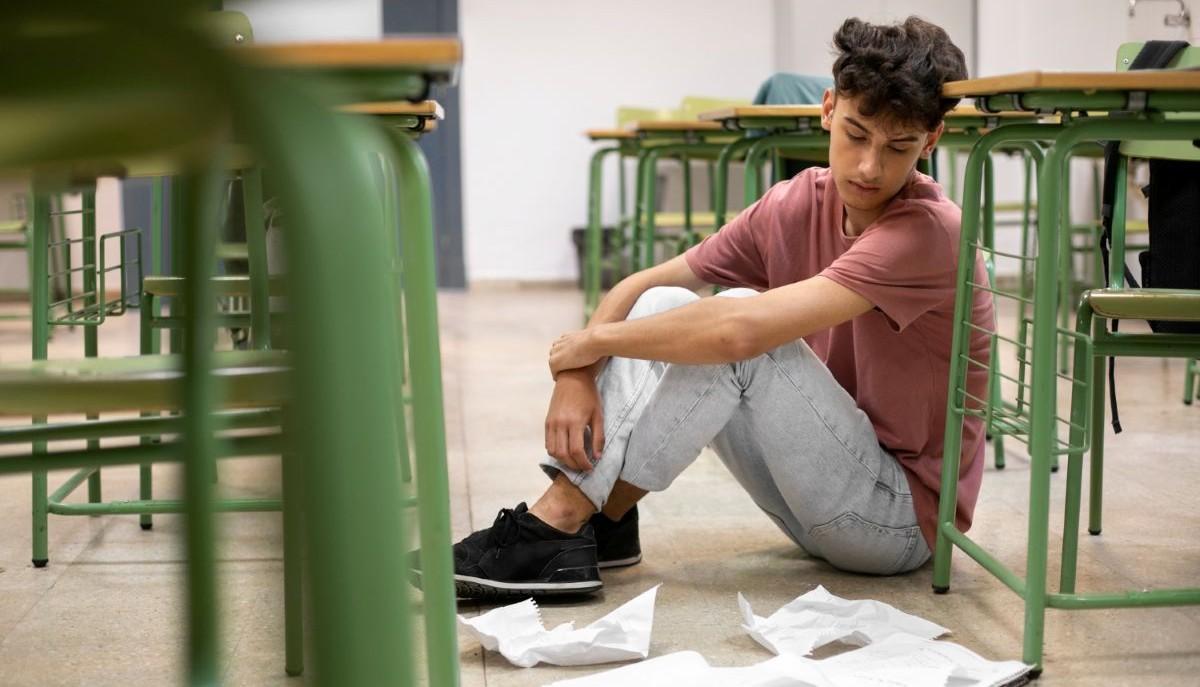 Studente seduto a terra tra i banchi