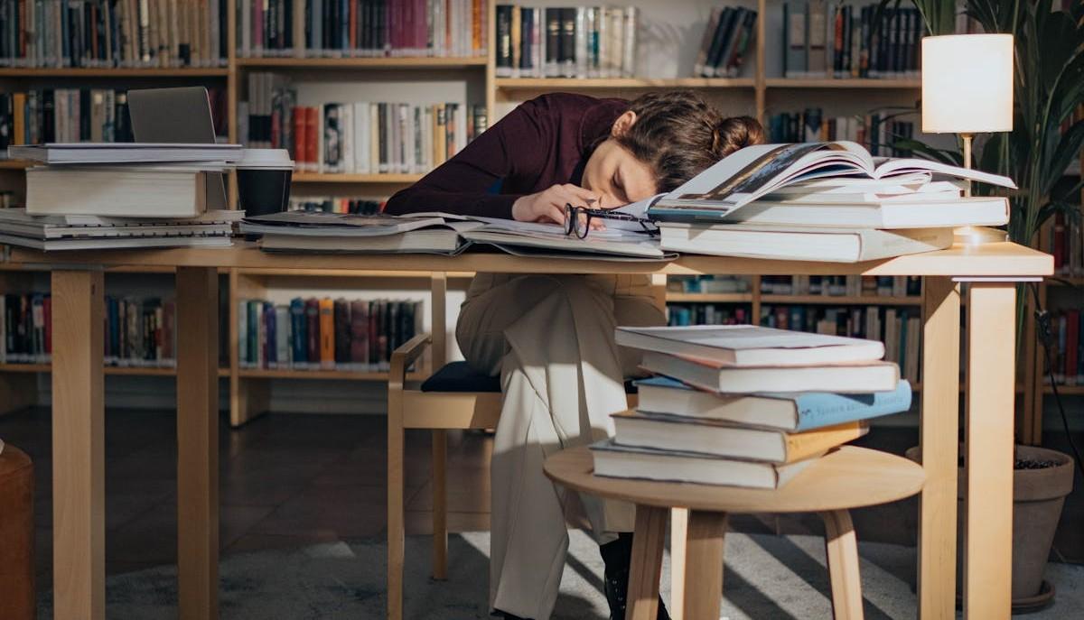 Studentessa dorme sulla scrivania tra i libri