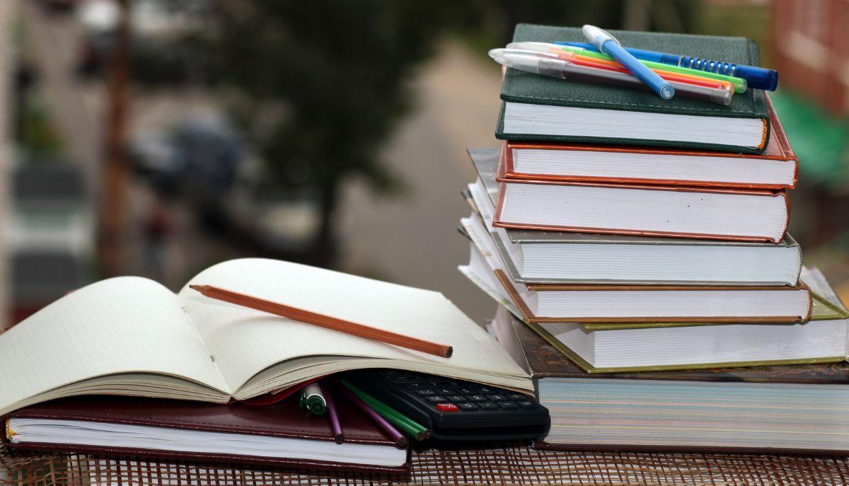 pila di libri e quaderni su una scrivania da studente