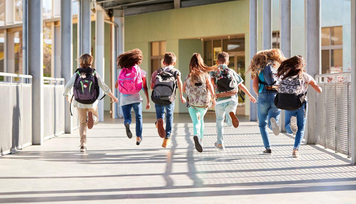 bambini corrono all'entrata di scuola