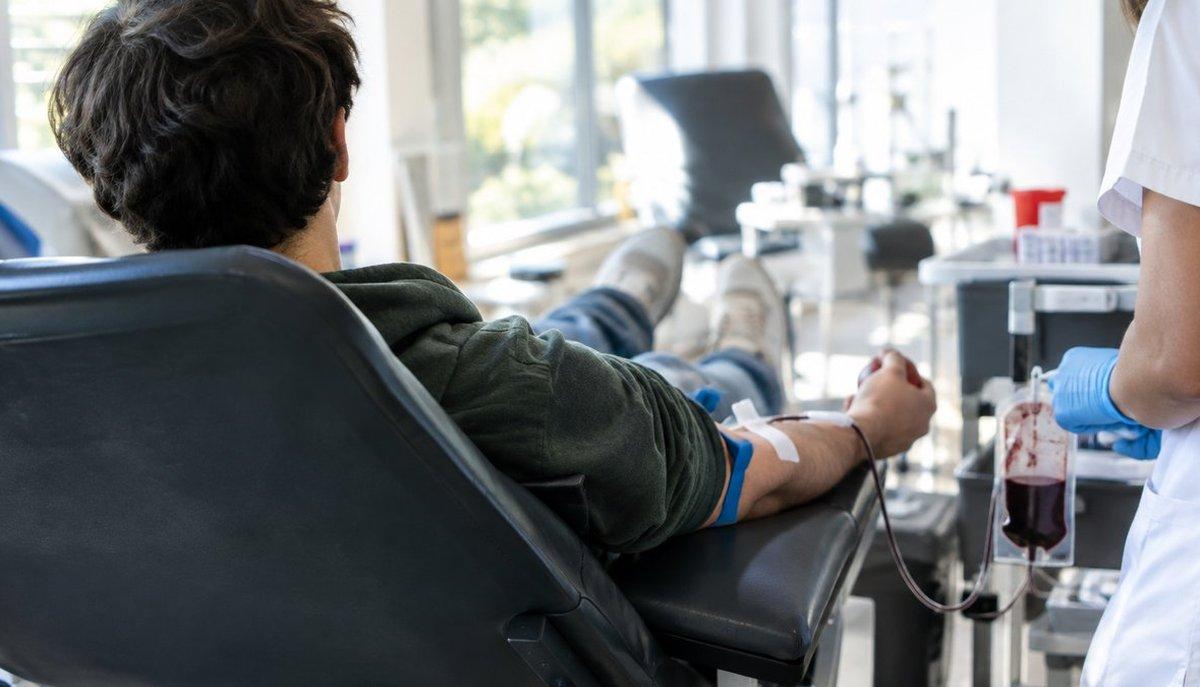 Illustrazione di un ragazzo che dona sangue su una poltrona assistito da un operatore sanitario