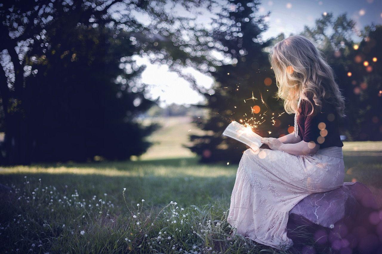 Bambina che legge un libro fantastico, le fiabe nella crescita dei bambini