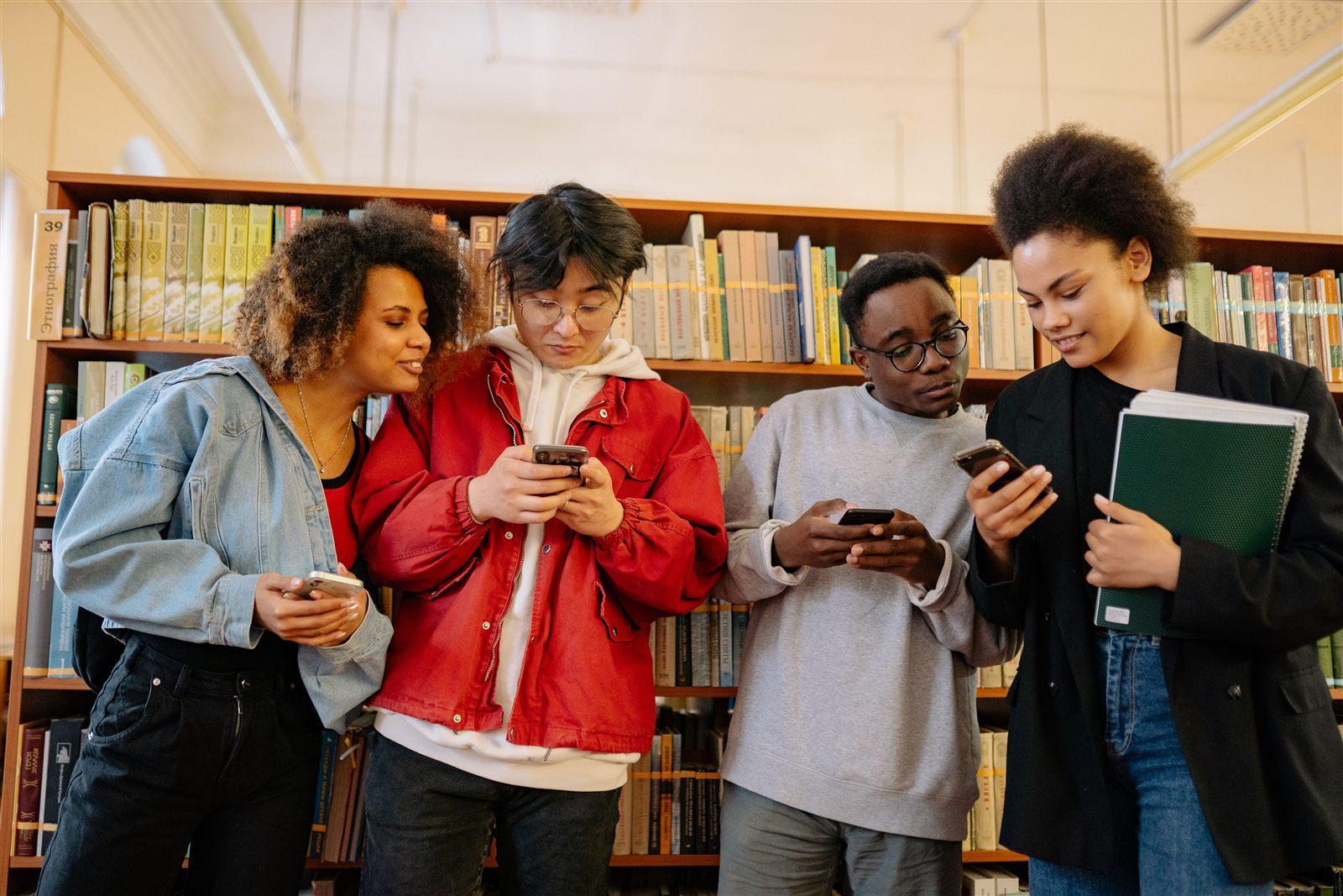 Studenti che usano lo smartphone in biblioteca, evoluzione del telefono cellulare