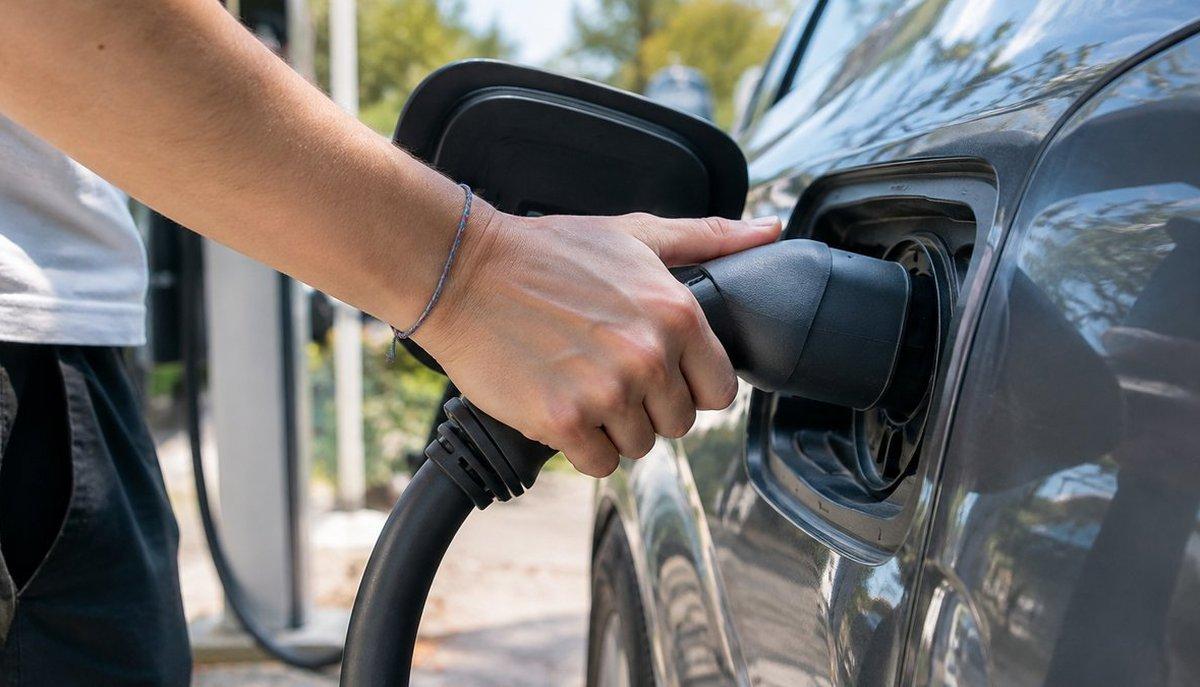 Illustrazione di una persona che collega il connettore di ricarica a un’auto elettrica