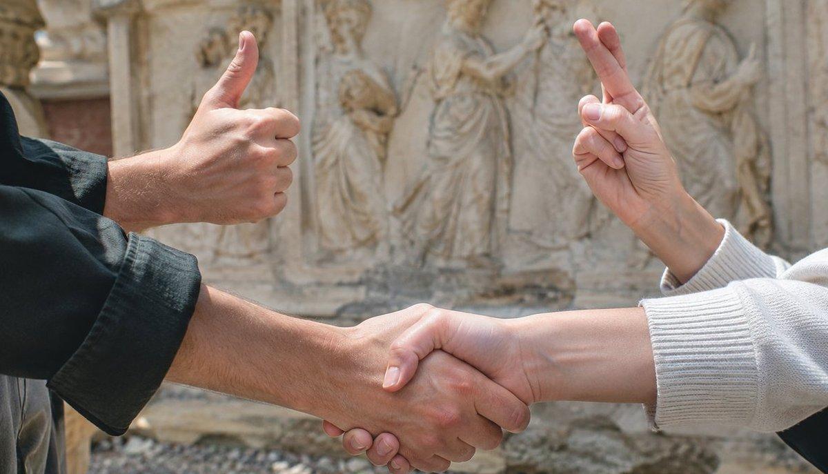 Illustrazione di due persone che si stringono la mano e fanno i gesti del pollice alzato e delle dita incrociate