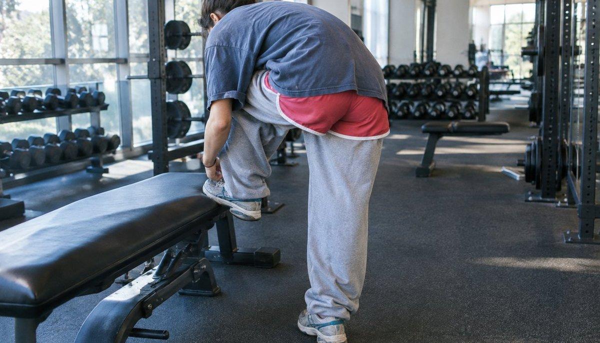 Illustrazione di un ragazzo che si allunga accanto a una panca in palestra